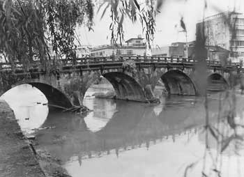 昭和49年、鹿児島市西田橋。当時の紙面には「川の流れには負けないが、時代の流れには逆らえず石橋取りこわしの話が聞かれるこのごろだ」。平成5年の８・６水害後、甲突川改修事業により平成8年2月に解体が始まった。