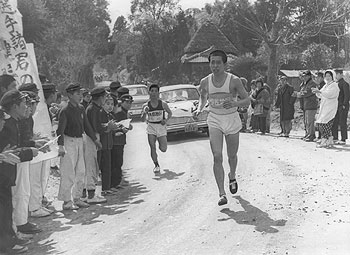 第3日5区、大口市の旧羽月中前を力走する大島・久保選手（左）と友情伴走する伊佐・荒田選手（右）。第9回大会は大島が初出場、伊佐は欠場した＝昭和37年2月26日