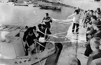 昭和58年12月、旧東町獅子島の片側港。当時の紙面には「２０年間小、中学生の通学の足として就航してきた東町獅子島の町営スクールボートが２学期いっぱいでその任務を終えた」とあり、３学期からスクールバスに替えると報じている。