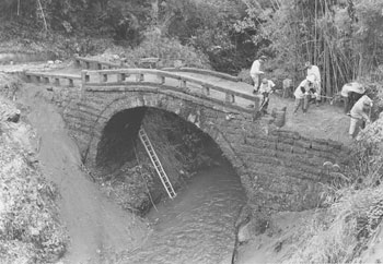 昭和５７年５月、旧大隅町の恒吉太鼓橋。紙面によると橋には雑木が茂り、土に埋もれているところもあったが、同町が文化財に指定したことで「七十年ぶりに“発掘”された」と報じている。