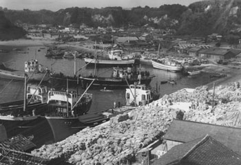 昭和３７年、旧志布志町の志布志港。当時の紙面によると、同港は平面荷揚げ場百四十メートルで「五百トン級貨物船が六隻も横着けすれば身動きもできない。でんぷん最盛期にはでんぷんの山で足の踏み場もなくなる」と伝えている。