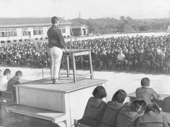 昭和３１年１１月、鹿屋中学校生徒会長の立会演説会。当時の紙面は「生徒会長の立候補者立会演説が同校グラウンドで、１２９７名の生徒が集まりひらかれた。候補者は各クラスから推された信望家ばかり」と伝えている。