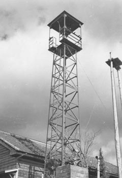 昭和３９年１２月、旧大根占町宿利原小のサイレン塔。紙面によると、塔は高さ１３メートル、紅色のペンキでぬり上げられ、工費１６万円。「ベルタイマーで午前８時、正午、午後６時の３回サイレンが鳴らされる」と伝えている。