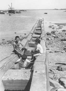 昭和３６年８月、旧佐多町の人間魚雷進水路。紙面によると「本土決戦を前に日本海軍が最後の運命をかけて作った新兵器の基地が同町間泊にあった。子どもたちが無心に遊ぶ海岸には、いまなお人間魚雷の発進に使った進水路が残っている」と伝えている。