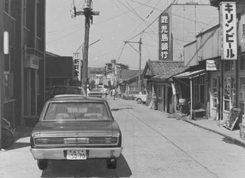昭和４９年６月、昔ながらの店舗が多い宮之浦の商店街。紙面によると「観光立島が行政の柱となり、それまでの島の需要中心の商売から、登山客や観光客をターゲットにする商売も考えなくてはならない。商店街としても課題として『お客に買っていただく』という商売意識に欠けており、売り上げ増のために意識改革も必要」などと伝えている。