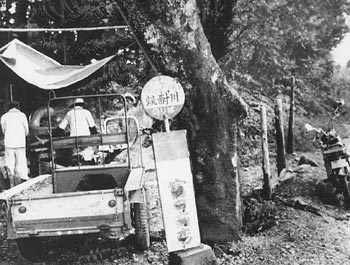 昭和４５年８月、県道屋久島循環線にある珍しい名前のバス停留所「焼酎川」。紙面では「あまりにも小さな川が多く、それにかける橋の名前に地名だけでは足らなくなって、近所に住む人の名前などもつけたりした。焼酎川は川の下流でヤミ焼酎を造っていたことにちなみ、にわかに名付けられたらしい。観光にも一役買って、『養老の滝・屋久島版』として関心を呼んでいる」と紹介している。