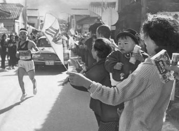 第1日、赤ちゃんを抱いて応援する中野選手（川辺）の奥さん、テルさんと愛息の明人ちゃん＝昭和41年2月18日、知覧町