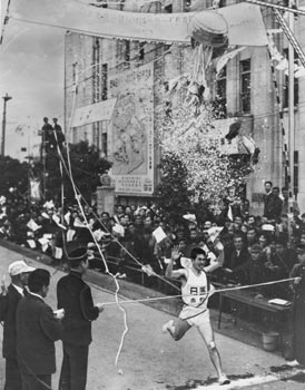 最終日、花ふぶきをあび優勝のテープを切る西野選手（日置）＝昭和42年2月22日、旧南日本新聞社前