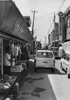 昭和４８年１１月、天城町平土野の商店街。当時の紙面では「天城町商工会は青年部を中心に活動し、８月には同町最大のまつりを開催、約６０００人の人出があった。徳之島空港をひかえているだけに観光客の定着を狙うが、平土野港に定期客船が寄港せず、大きなネックになっている。今後、中央通りにはアーケードを取り付ける計画」などと紹介する。