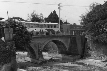 昭和４５年８月３日、和泊港近くの奥川にかかる南洲橋。紙面によると「幕末に西郷隆盛が配流の苦しみをなめた、南洲たっ居の地と結ぶ橋ということで、南洲橋と名付けられたという。大正１２年に完工、島内産の石灰岩で造られためがね橋で、このような立派な橋は大島郡内にほかに例がない。時代の移り変わりで交通量が増え、１０年前に拡幅した」などと紹介している。