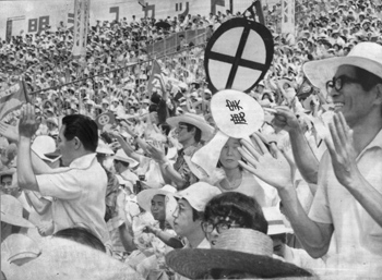 昭和４９年夏の全国高校野球選手権準決勝、丸に十の字のウチワが舞う鹿児島実の応援団席。紙面は「三塁側アルプススタンドは通路まで占領する大応援団。９回裏、『昨日に続き再び延長に』と新たな興奮に包まれたが、サヨナラ負けを喫し、目を伏す人の姿も。整列して一礼する選手たちには『よくやった。ありがとう』の声が浴びせられた」と報じている。