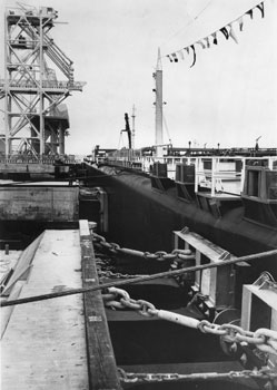 昭和４４年９月、衝撃を吸収する特殊構造の桟橋に横付けしたかいもん丸。「『かいもん丸』の入港で操業を始めた日石喜入基地。わが国の経済発展に新機軸をもたらすとともに後進地域といわれる鹿児島県の地域開発に大きくプラスするものとして期待される」と紙面は伝えている。
