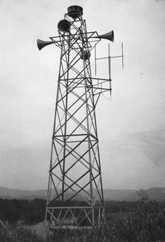 昭和４０年４月、サイレント拡声器のテストを始める“放流警報局”。当時の紙面は「警報局は建設省が川内川流域９カ所に施設した無人局。鶴田ダムが大量の貯水を人工放流した場合、急に川の水位が上がるので、下流の被災防止のために建設した」と伝えている。