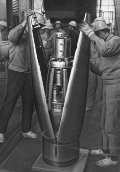 昭和４０年３月、内之浦町（現肝付町）のロケット実験場から打ち上げるラムダ３型３号機を組み立てる東京大学ロケット実験班。紙面は「同機は初の“銀河Ｘ線”測定のため、日没後の発射を選んでいる。発射６時間前から準備にとりかかった」と伝えている。