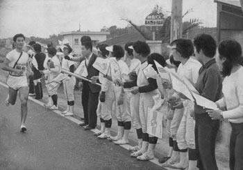 昭和４６年２月１４日、串木野市（現いちき串木野市）。「全国一の腕をもつ串木野女子高ソフトボール部のオゴジョ」が沿道から声援、「選手はニコニコとうれしそう」と伝えている。