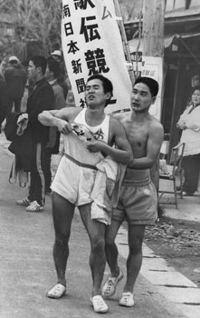 昭和４７年２月１４日、第１９回県下一周駅伝第３日の西太良教場中継点（現伊佐市）。バトンタッチ後、沖縄・比嘉選手（左）を介抱する茅野選手（川辺）。