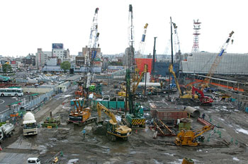 平成１５年５月、大型クレーンが立ち並び、建設が進む西鹿児島駅ビル（現アミュプラザ鹿児島）。当時の紙面は「３月に着工し、現在は土台を支えるコンクリートくいをつくる工事が進む。工事現場には多くの大型クレーンが登場、道行く人の目をひいている」と報じた。