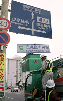 平成１６年３月１日、九州新幹線部分開業まであと１２日と迫り、鹿児島市内で始まった道路案内標識の変更作業。紙面は「同市山下町の県道鹿児島蒲生線では、道路標識の『西鹿児島駅』の文字の上に『鹿児島中央駅』と書いたアルミ製のプレートをかぶせてビス留めした」と伝えている。