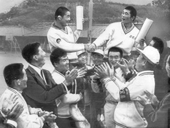 昭和４６年１０月、和歌山国体、陸上、レスリング、軟式庭球教員男子、弓道高校男子近的が続々と優勝した。写真はレスリングで優勝した有村選手と平田選手を肩にのせ喜ぶ鹿児島県関係者。紙面は「やや低迷気味だった鹿県勢は、競技開始３日目にやっと実力を見せた。『あと２日も、この勢いで突っ走るぞ』と意気は大いに上がっている」と報じている。