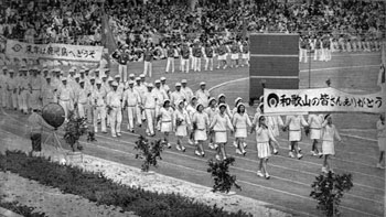昭和４６年１０月、第２６回国民体育大会秋季大会は和歌山県内で２７競技が繰り広げられたが、閉会式で全日程を終了した。写真は「和歌山のみなさんありがとう」「来年は鹿児島へどうぞ」の横幕を手に閉会式の入場行進する鹿児島県役員選手団。紙面は「総合優勝は和歌山が飾り、鹿児島県は６位に躍進。選手強化が着実に進んでいることを示した」と報じている。