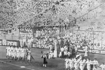昭和５９年８月８日、第６６回夏の全国高校野球選手権大会が甲子園球場で開幕。１４日間にわたる熱戦の火ぶたを切った。写真は沖縄水産に続いて行進する鹿児島商工（現樟南）チーム。紙面は「突き抜ける青空、雲一つない。夏の燃える太陽が祝福する。日ごろ鍛えた技と力をぶつける球児の“熱いドラマ”が始まった」と報じている。