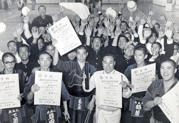 昭和４７年１０月太陽国体秋季大会、２日目から鹿児島県勢は早くも８競技で優勝７、準優勝４を飾った。紙面では「地元、鹿児島県の選手は故郷の国体で初日から、すばらしいすべり出し。純血を象徴する高校生を中心に、しかも武の国の伝統を維持して柔剣道を軸にした価値ある快進撃の開始だ」と高校勢の活躍をたたえている。写真は剣道高校の部優勝の鹿児島商工高。