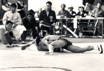 昭和４７年１０月太陽国体秋季大会、レスリングの一般グレコローマン５２キロ級決勝。写真は鹿児島代表の平山（国分自衛隊）が三重の宇野にフォール勝ち。「五輪銀メダリストの平山は、あたりを払う貫禄。あっという間に後ろに回って相手を転がし７ポイント、次の瞬間には余裕を持って立て四方の形にくみかえてフォールを決めた」と報じている。