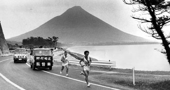昭和４８年２月１０日、第２０回県下一周駅伝第１日目。開聞岳をバックに、力走する選手。６区・頴娃町で川辺チームの市坪選手が、肝属の小牧選手を抜く。