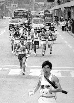 昭和４８年、第２０回県下一周駅伝第３日。写真は３日目川内市内で、川井田（肝属）を先頭に浜田（鹿児島、２位）ら各チームのエースが走る一区の様子。紙面では「１区は１５．３キロの長丁場。レースの主導権を握ろうと各チーム、とっておきのエースをそろえた。鹿児島の浜田は自身の１８回大会で作った記録を２３秒縮め、区間新記録でゴールした」と報じている。
