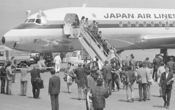 昭和４７年４月１日、新鹿児島空港オープン初日、香港からチャーター機で飛んできた観光団の一行。紙面では「約８万人の人出でごった返す空港周辺で、ひときわ花やぐ国際線ロビー。『カゴシマ・エアポート、ベリーナイスネ』－。ミニやパンタロンの若い娘さん、派手に着かざった中年婦人、スマートな紳士たち…。顔こそ日本人と違わないが、香港からの第一便が到着した同ロビーは“国際カラー”であふれた」と報じている。