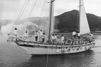 昭和５３年１０月２９日朝、炬火を乗せ鹿児島市の平川ヨットハーバーを出発する「セントアロー号」。紙面では「県民体育大会を目前に、奄美大島のヨットマンら海の男たちが、鹿児島市で燃え続けている東京オリンピックの聖火リレーの火をヨットで奄美大島に運ぶため、荒天の中、平川ヨットハーバーを出港した」と報じている。
