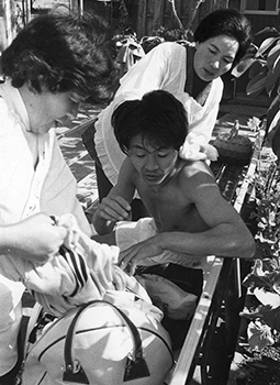 昭和４９年２月１０日、駅伝第１日、指宿駅前中継所で、精根尽きた選手のからだをふき、介抱する婦人会のおばさん。