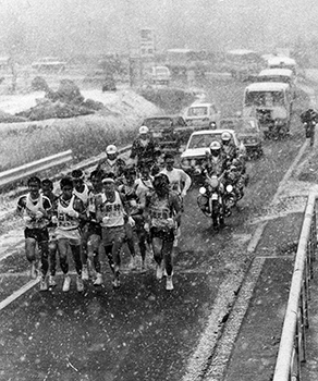 昭和４９年２月１１日、駅伝第２日、日置郡金峰町で、駅伝につきものの雪が、ことしも舞った。顔をさげ一団となって力走する選手。