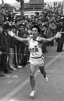 昭和４９年２月１１日、駅伝第２日、出水市役所前で肝付を抑えゴールに飛び込む鹿児島の鶴丸選手。紙面では「２日間の総合は、第１日首位をとった鹿児島が累計１３時間４４分４５秒で昨年に続いて２連勝、通算９回目の優勝を飾った。総合第２位は肝付の１３時間４６分７秒、３位は第２日、郷土へトップで入った出水の１３時間５３分１０秒、以下日置、川辺、姶良、川薩、曽於、指宿。第１日健闘した熊毛は１０位、続いて伊佐、大島だった」と報じている。