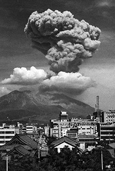昭和４２年６月１４日、２９００メートルまで噴煙を上げた桜島。紙面では「鹿児島地方気象台桜島火山観測所では４７ミクロンの地震と鳴動を２０秒間観測、赤く焼けた噴石が５合目までとんで数カ所で山火事を起こし１時間燃えつづけた。火口から南側へ３．３キロ離れた古里温泉では空振で窓ガラスが割れ、しょうじのはずれた家もあった。爆発はことし３９回目」と報じている。