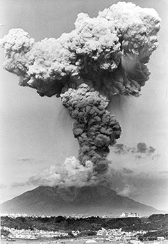 昭和６０年９月９日午後４時４４分、鹿児島市中山町から撮影した高さ４０００メートルまで上がった桜島の噴煙。紙面では「爆発後も噴煙が連続、風が弱かったためか、上空で大きく『Ｙ』の字形に広がって滞留、灰雲がいくつもの層をつくった。まもなく噴煙は東の方向へゆっくり流れ始め、鹿児島市黒神町や垂水市牛根境などでは目も開けておれないほどのドカ灰となった。曽於郡輝北町でも路面がたちまち白っぽく染まった」と報じている。