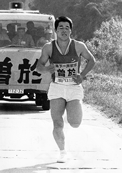 第２２回県下一周駅伝第２日、４区９キロ地点を力走する曽於・瀬戸口選手。過疎化がすすみ、一時は駅伝出場が不可能とさえいわれた農村や離島チーム。これらのチームを立て直したのが、いわゆるＵターン帰省者や、若い自営業者たちだ。第２日に出場したこれら自営者たちは８人。その中でも、この日曽於チームの４区を走った瀬戸口三郎選手は異色の存在だった。