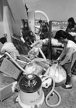 平成元年５月１５日、６０日間ともに過ごしたパビリオンの後片付けを手伝うコンパニオンたち。８８万人が訪れた鹿児島市谷山１号用地のサザンピア２１。まだ祭りの余韻のさめやらぬというのに１５日朝、早くも撤去作業が始まった。作業員の間から「もったいないなあ」との声も聞かれる中、取り壊し作業は着々と進んだ。